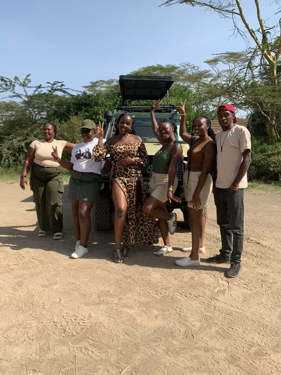 A group of friends celebrating beside the safari vehicle in the bush